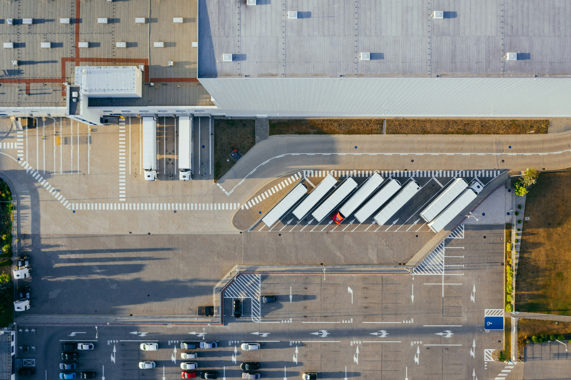 Aerial view of a truck yard with parked trailers and cars